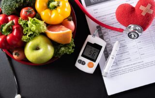 Glucose monitor on a table with food and medical notes.